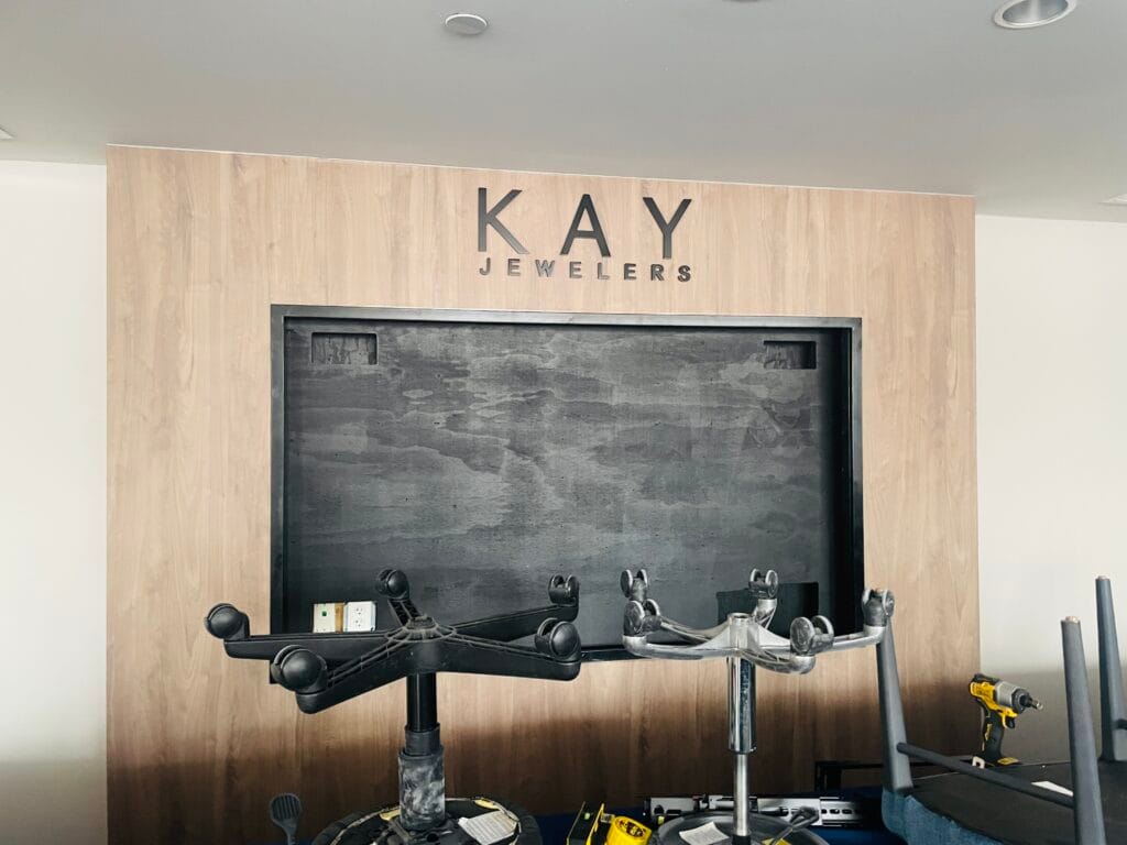 Retail display niche with the screen removed, showing backer board and wall mount arms