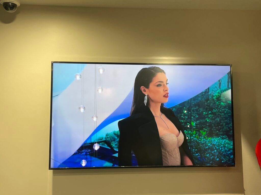 Wall display screen showing a jewellery advertisement with a dome camera above