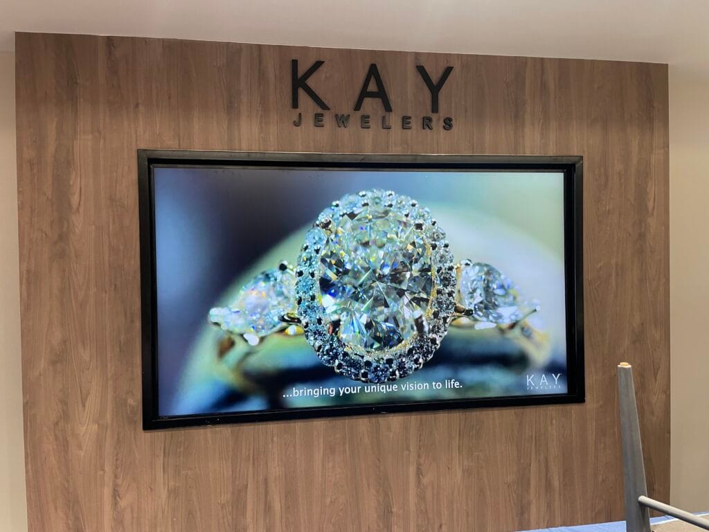 Wall-mounted retail display screen showing a diamond ring advertisement