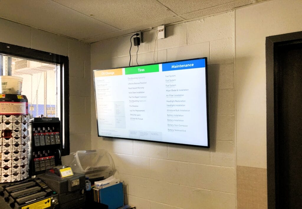 Wall-mounted menu board screen listing service options and pricing