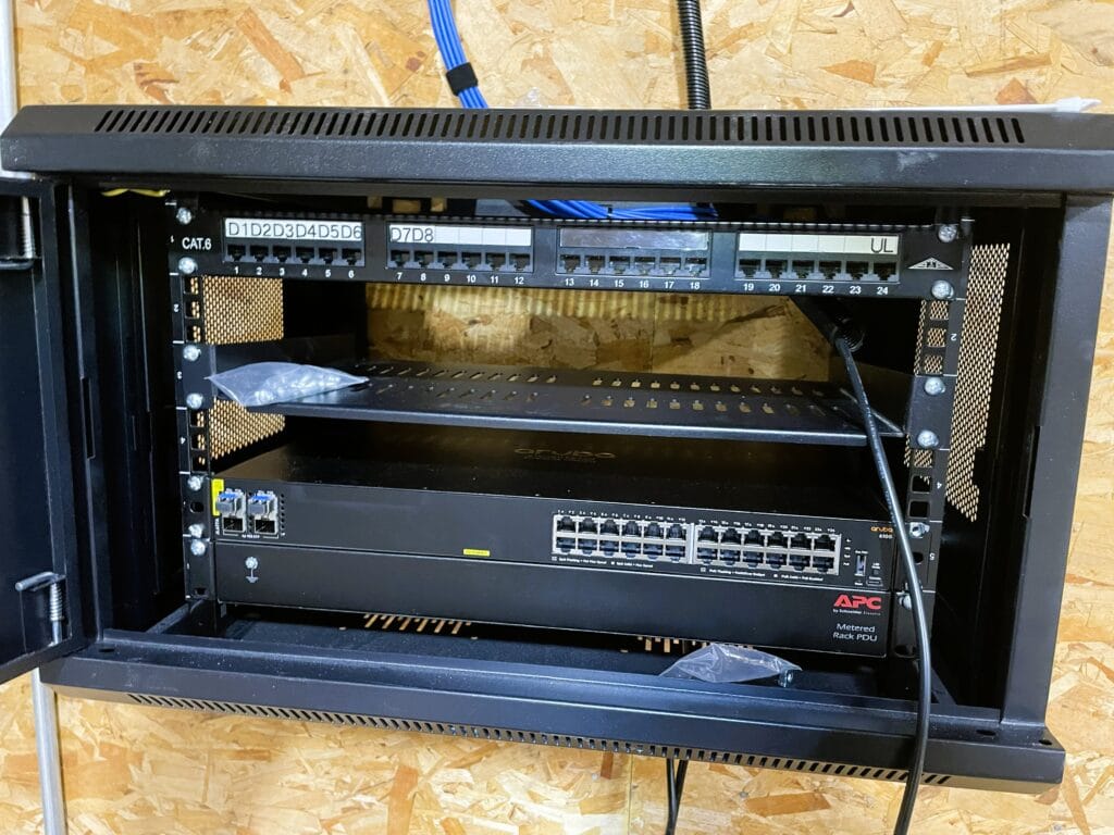 Wall cabinet with a labelled CAT6 patch panel, Aruba switch and APC power distribution unit