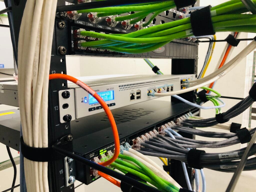 CAT6 patch panel and Cisco switch patched with coloured cables in a branch rack