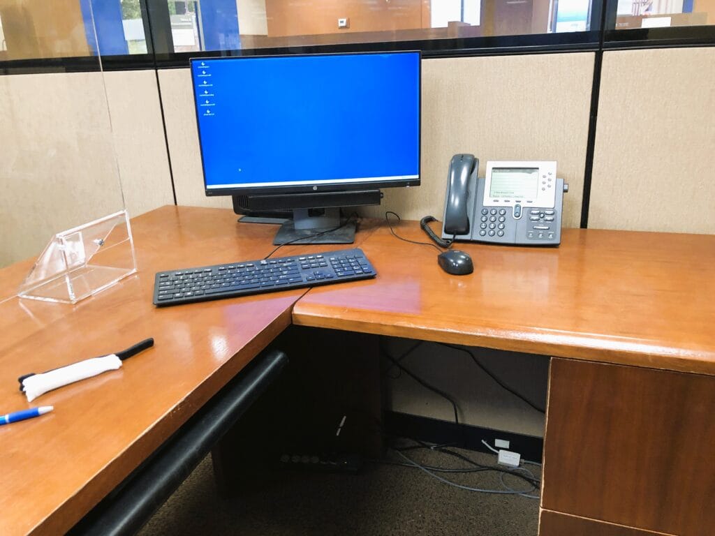 Cubicle desk with a monitor, keyboard and Cisco IP desk phone
