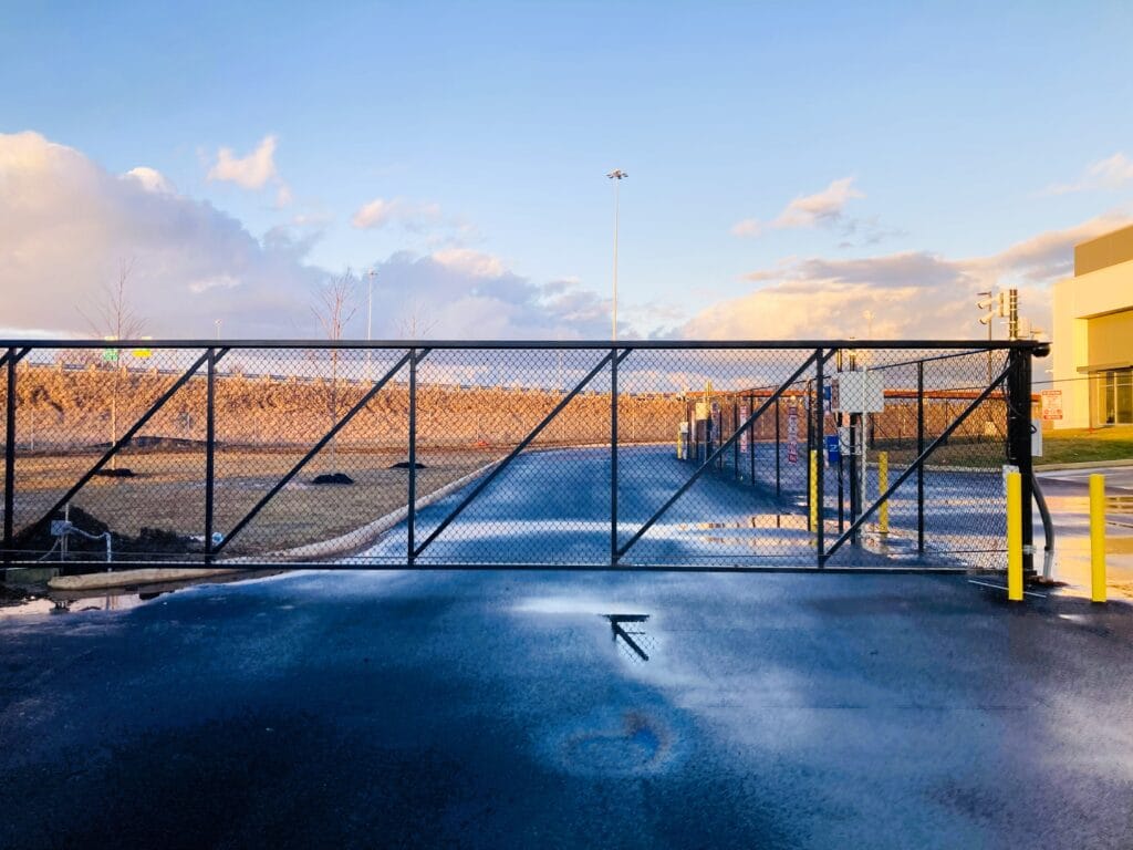 Black chain-link sliding gate with access control equipment mounted on the post